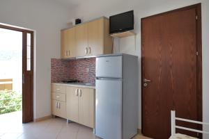 a kitchen with a refrigerator and a tv on top at Pellumb Apartments in Ksamil