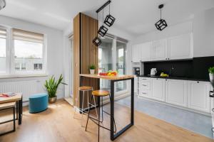 a kitchen with white cabinets and a island with bar stools at Otwock PREMIUM Apartment- CENTRUM PKP in Otwock