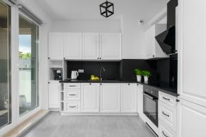 a kitchen with white cabinets and black counter tops at Otwock PREMIUM Apartment- CENTRUM PKP in Otwock +8 photos