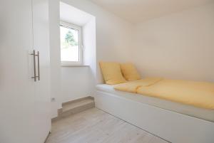 ein Bett in einem weißen Zimmer mit einem Fenster in der Unterkunft Apartments D&V in Kotor