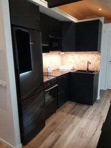 uma cozinha com electrodomésticos pretos e piso em madeira em Kolmården Apartments & Cottages em Stavsjo
