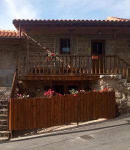 uma cerca de madeira em frente a uma casa com flores em Habitación do Xurés em Maus de Salas