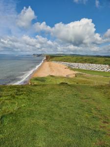 vistas a una playa de arena con el océano en FRESHWATER BEACH HOLIDAY HOME, en Burton Bradstock