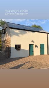 a large white building with green doors on it at Blackshaw's Studio in Scolboa