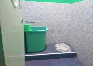 a bathroom with a green trash can and a toilet at Hotel Bukit Panembahan in Sunggal