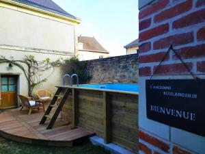 a wooden deck with a swimming pool next to a building at L'Ancienne Boulangerie in Chavagnes
