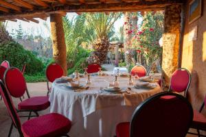 a table with red chairs and a white table cloth at Maison Nomades in Aït Boukha