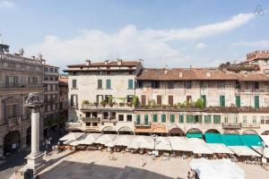 un groupe de bâtiments avec tables et parapluies dans l'établissement Truly Verona - Delle Erbe suites, à Vérone