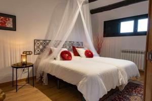 1 dormitorio con cama blanca y almohadas rojas en Ca la Cinta de Maldà, en Maldá
