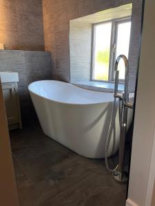 a white bath tub in a bathroom with a window at The Tavern at Hale in Milnthorpe