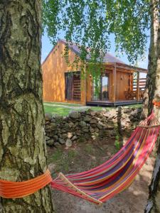 a hammock in front of a log house at Kamienny Ogród Holiday Park in Mikołajki