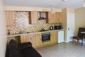 a kitchen with wooden cabinets and a stove top oven at The Village Bed and Breakfast in Cushendall