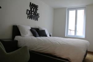 1 dormitorio con 1 cama blanca con silla y ventana en Salt&Sea, en Middelkerke