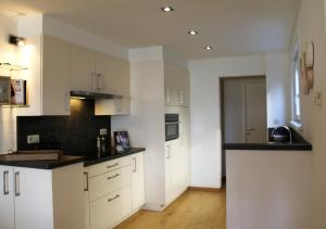 Una cocina con gabinetes blancos y encimeras negras. en Salt&Sea, en Middelkerke