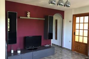 a living room with a tv and a red wall at La casa de Aneta in Barbastro