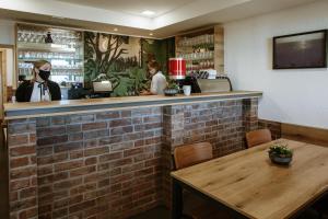 a restaurant with a brick bar with a woman wearing a mask at Dom na Slivnici in Cerknica