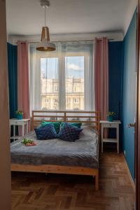 a bedroom with a bed with blue walls and a window at Apartament Eliza in Warsaw