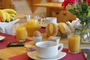 una mesa cubierta con tazas de zumo de naranja y pan en La Pradella, en Bolquere Pyrenees 2000