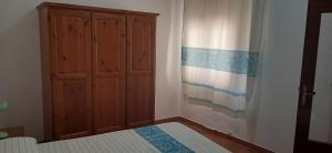 a bedroom with a bed and a wooden cabinet at Il pergolato in Bari Sardo