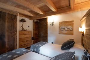 two beds in a room with wooden ceilings at Dolomiti Chalet degli Abeti in Campitello di Fassa