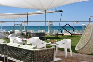 eine Terrasse mit Tischen und Stühlen und Strand in der Unterkunft The Sense Experience Resort in Follonica