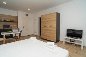 a white bedroom with a large bed and a tv at Aparthotel Primorsko in Primorsko