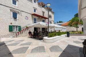 a patio with tables and umbrellas in front of a building at Apartments and Rooms Mišić in Trogir