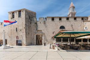 a large stone building with a flag in front of it at Apartments and Rooms Mišić in Trogir