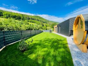 un patio trasero con una valla y un patio verde en Voralpen Lodge - Ferienhaus mit Gym, Sauna & Hot Tub, en Traisen