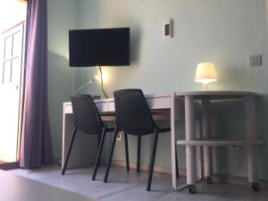 a room with a desk with two chairs and a television at Atico Andalucia Plaza in Tarifa