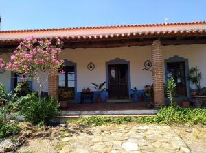 una casa con un porche con flores rosas en Aproveite o sabor do Alentejo, en Vila Verde de Ficalho