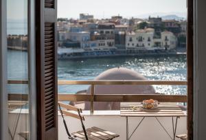 einen Tisch auf einem Balkon mit Blick auf das Wasser in der Unterkunft Amphitrite Hotel in Chania