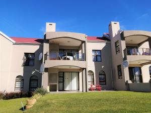 een groot wit gebouw met een groene tuin bij 2-Bedroom Apartment within 1km of The Point Beach in Mosselbaai