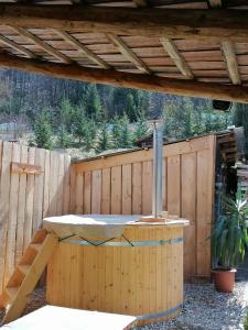 una bañera de hidromasaje al aire libre en un patio trasero con una valla de madera en Csillag Vendégház, en Répáshuta