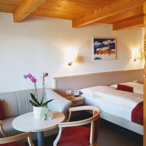 ヴィルダースヴィルにあるChalet-Gafri - BnB - Frühstückspension - Service fast wie im Hotelのベッド、テーブル、ベッド、ソファが備わるホテルルームです。