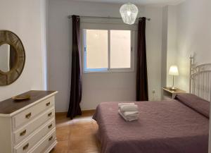 sypialnia z łóżkiem, komodą i oknem w obiekcie Center Holiday Corralejo 2 w Corralejo