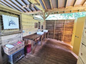 um quarto de madeira com uma mesa e 2 lavatórios num camarote em La Wigwam Rouge du Domaine du Pas de l'âne em Mios