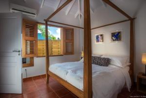 a bedroom with a canopy bed and a window at Villa Laucaly Orient Bay in Saint Martin