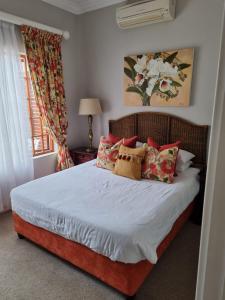 een slaapkamer met een bed met rode en witte kussens bij Pearl Cottage in Durban +24 foto's