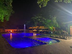 a swimming pool with a fountain at night at El Roi Guest Lodge in White River