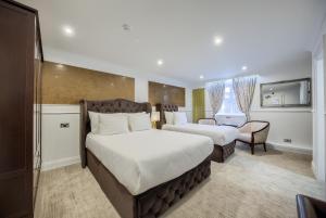 une chambre d'hôtel avec deux lits et une chaise dans l'établissement Grosvenor Hotel, à Stratford-upon-Avon