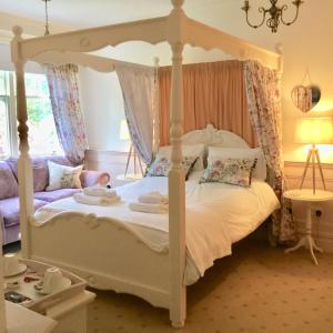 ein Schlafzimmer mit einem weißen Bett mit Baldachin in der Unterkunft Storrs Gate House in Bowness-on-Windermere