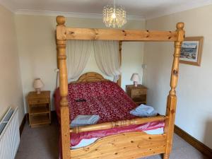 a wooden bed in a bedroom with two night stands at Longstone farm in Helston