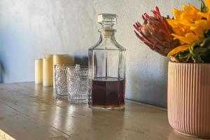 eine Glasflasche auf einem Tisch neben einer Blumenvase in der Unterkunft Falling Waters in Nottingham Road