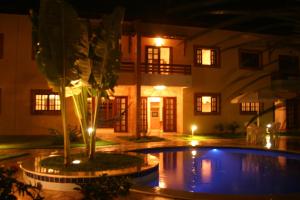 a pool in front of a house at night at CostaSol Pipa Chalés in Pipa