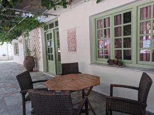 a patio with a wooden table and chairs and windows at Pension Irene in Sougia
