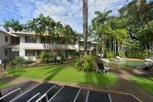 a yard with chairs and a swimming pool and a house at Reef Terraces on St Crispins - Villa 2 in Port Douglas