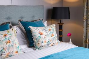 Una cama con almohadas azules y blancas y una lámpara. en Killarney Dromhall Hotel en Killarney