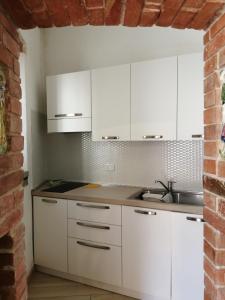 a kitchen with white cabinets and a brick wall at Per Due in Porto Santo Stefano
