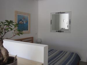 ein weißes Schlafzimmer mit einem Spiegel und einer Pflanze in der Unterkunft MONOLOCALE SAN PANTALEO in San Pantaleo